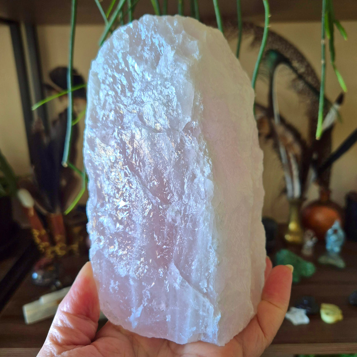 A hand holding a rose quartz crystal lamp with a reflective surface.
