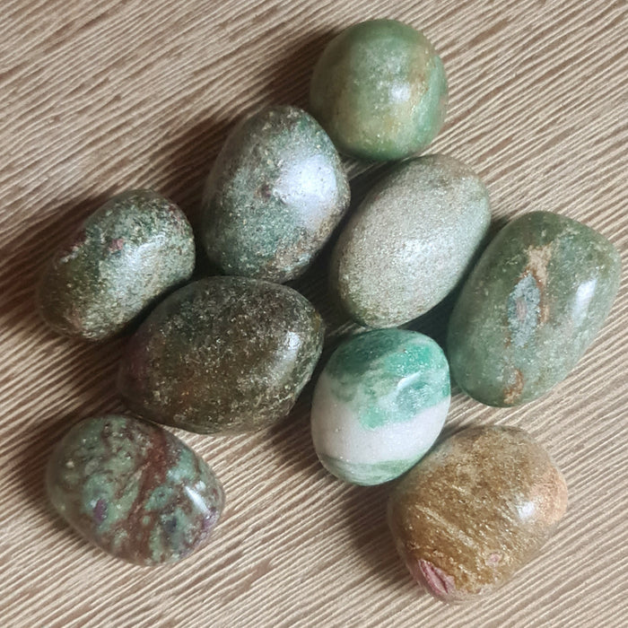 A collection of polished Ruby Fuchsite tumble stones with varying shades of green, brown, and hints of pink and white.