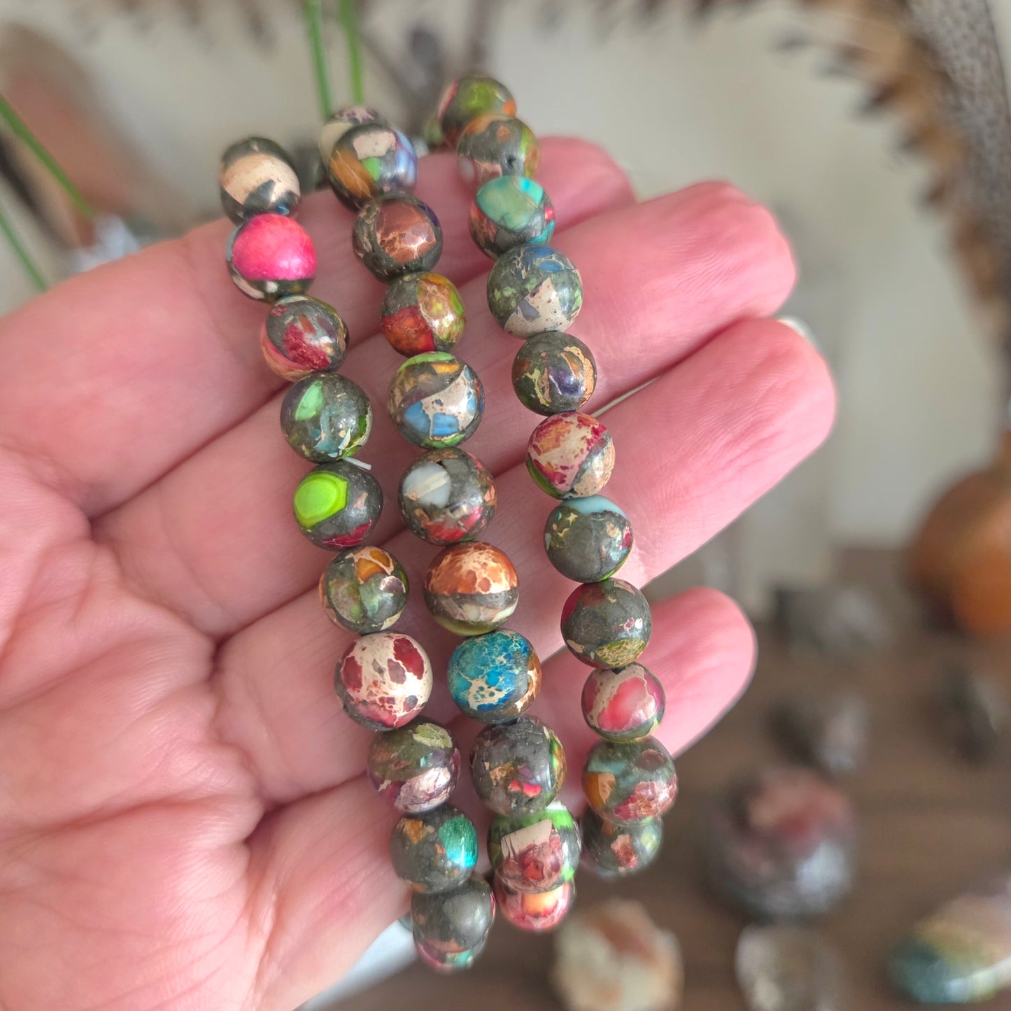 Hand holding a stack of multicolored beaded bracelets with a blurred background