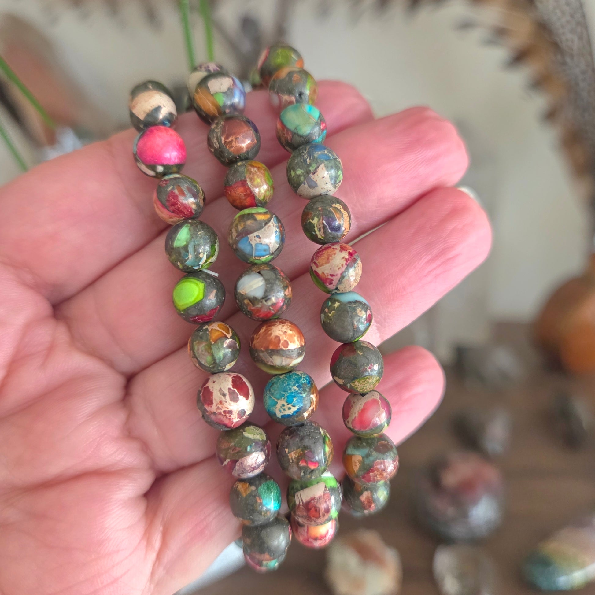 Hand holding a stack of multicolored beaded bracelets with a blurred background