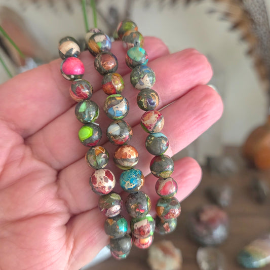 Hand holding a stack of multicolored beaded bracelets with a blurred background