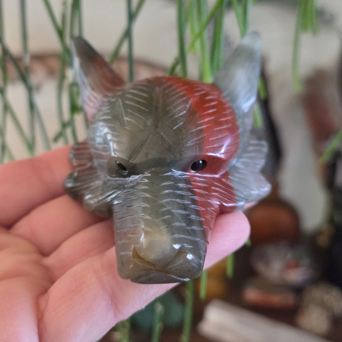 Hand holding a crystal elephant figurine with a blurred natural background
