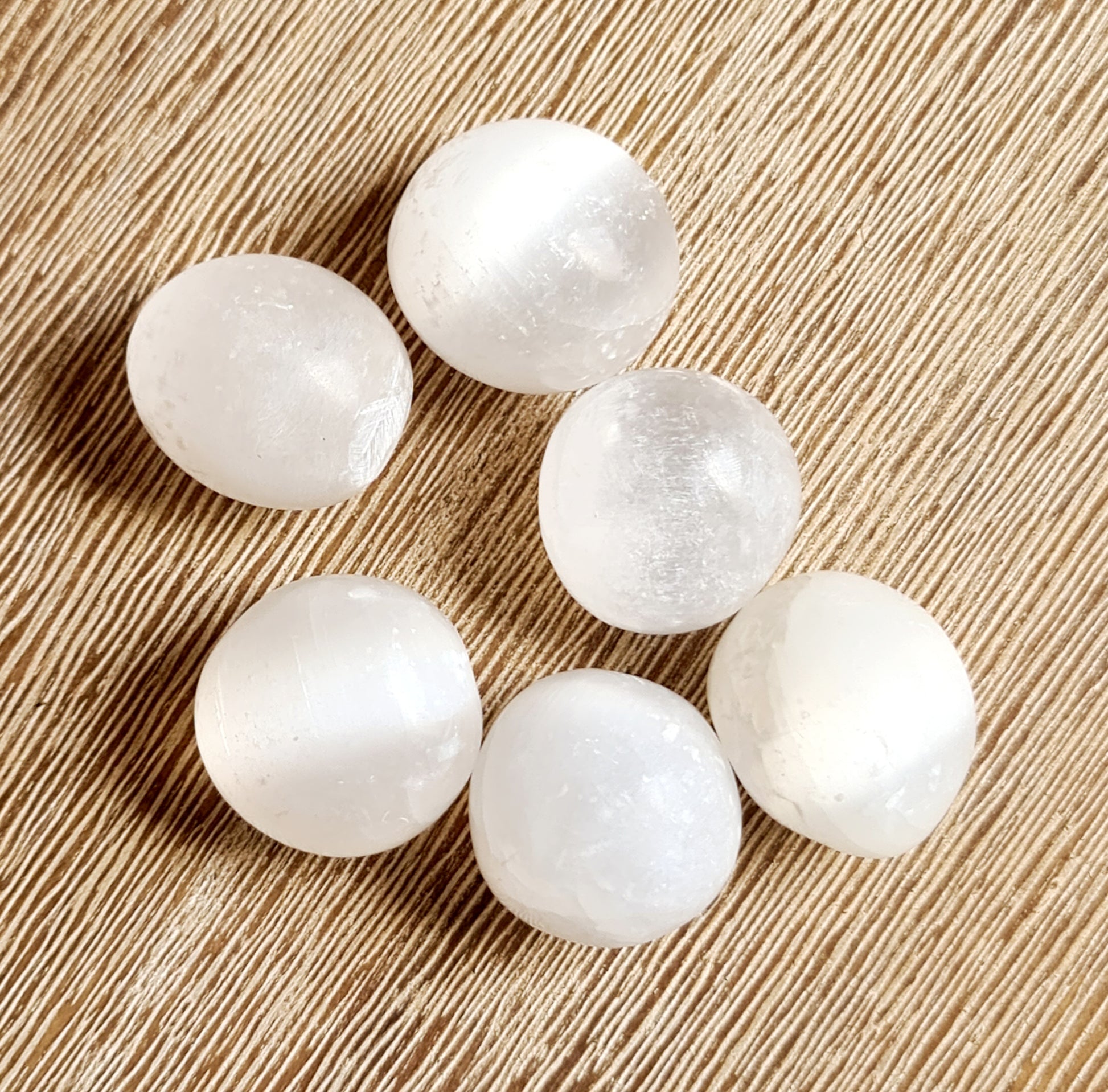 A collection of selenite crystal balls on a beige background.