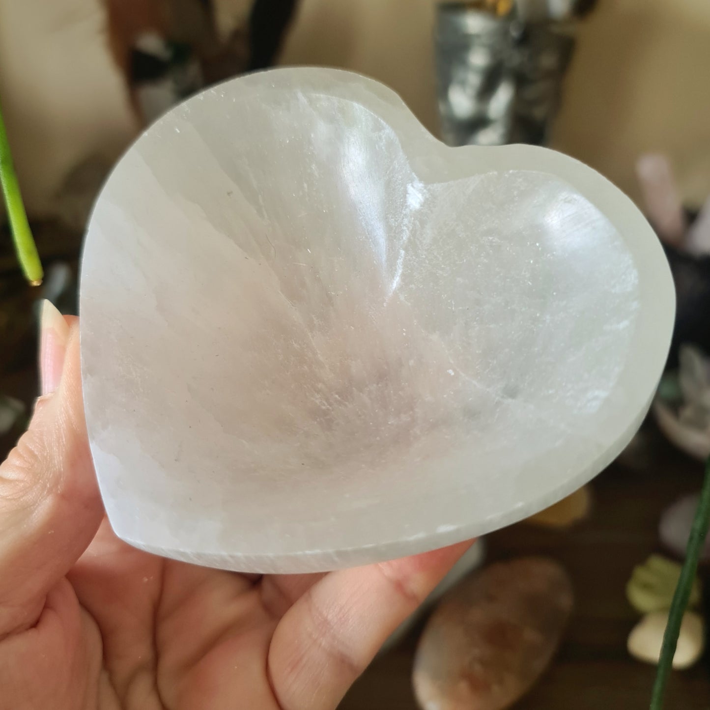 A heart-shaped selenite crystal bowl being held by a person.