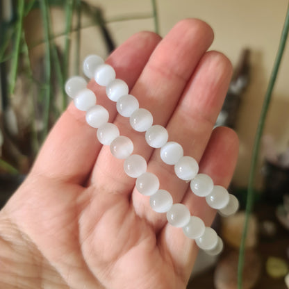A person's hand holding a Selenite beaded bracelet with a solid white color.