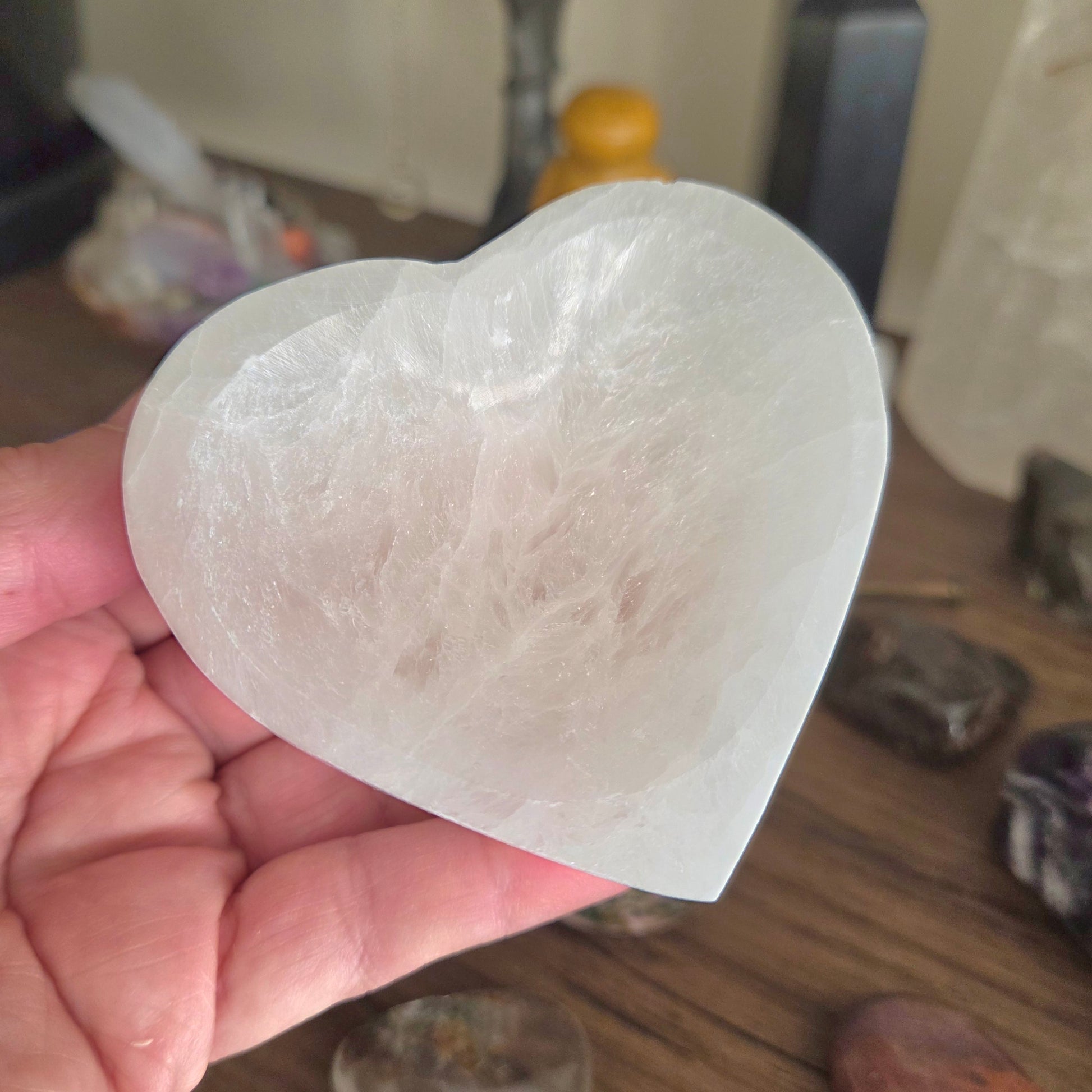 Heart-shaped crystal held in a hand with a blurred background