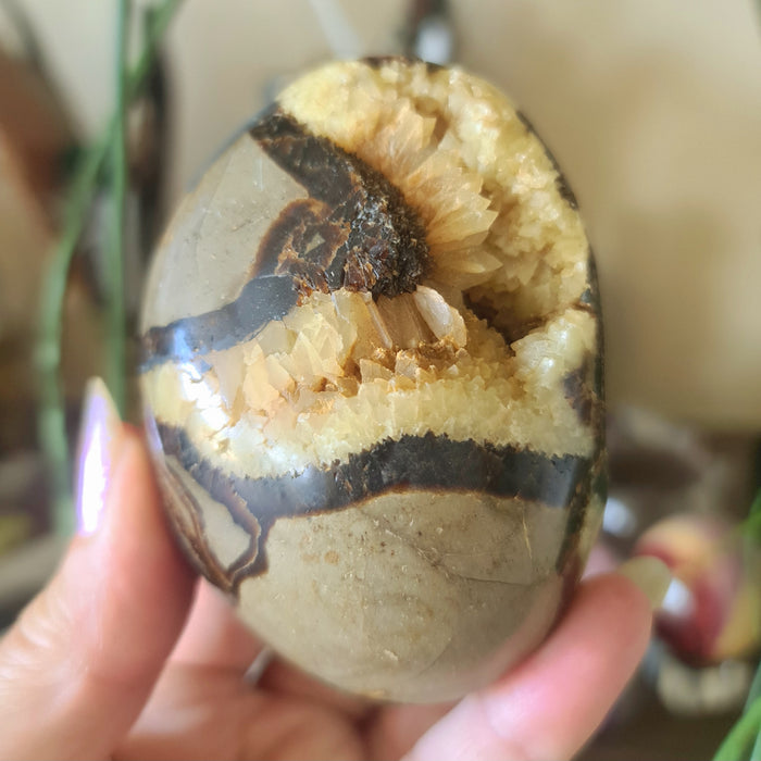 yellow and brown crystal held in a hand