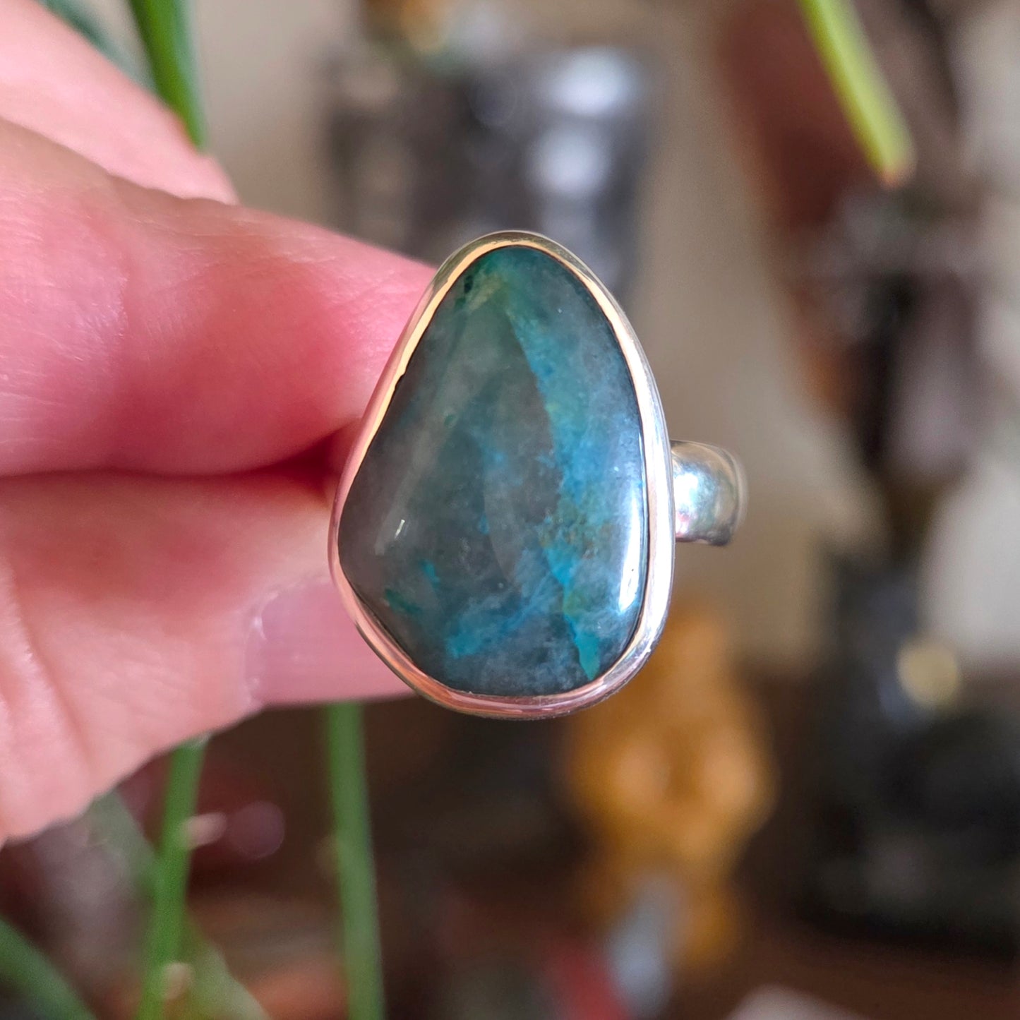 Ring with a large blue stone held in a hand against a blurred background