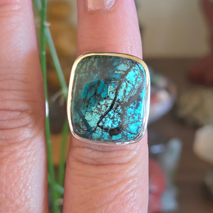 Turquoise stone ring on a finger with a blurred background
