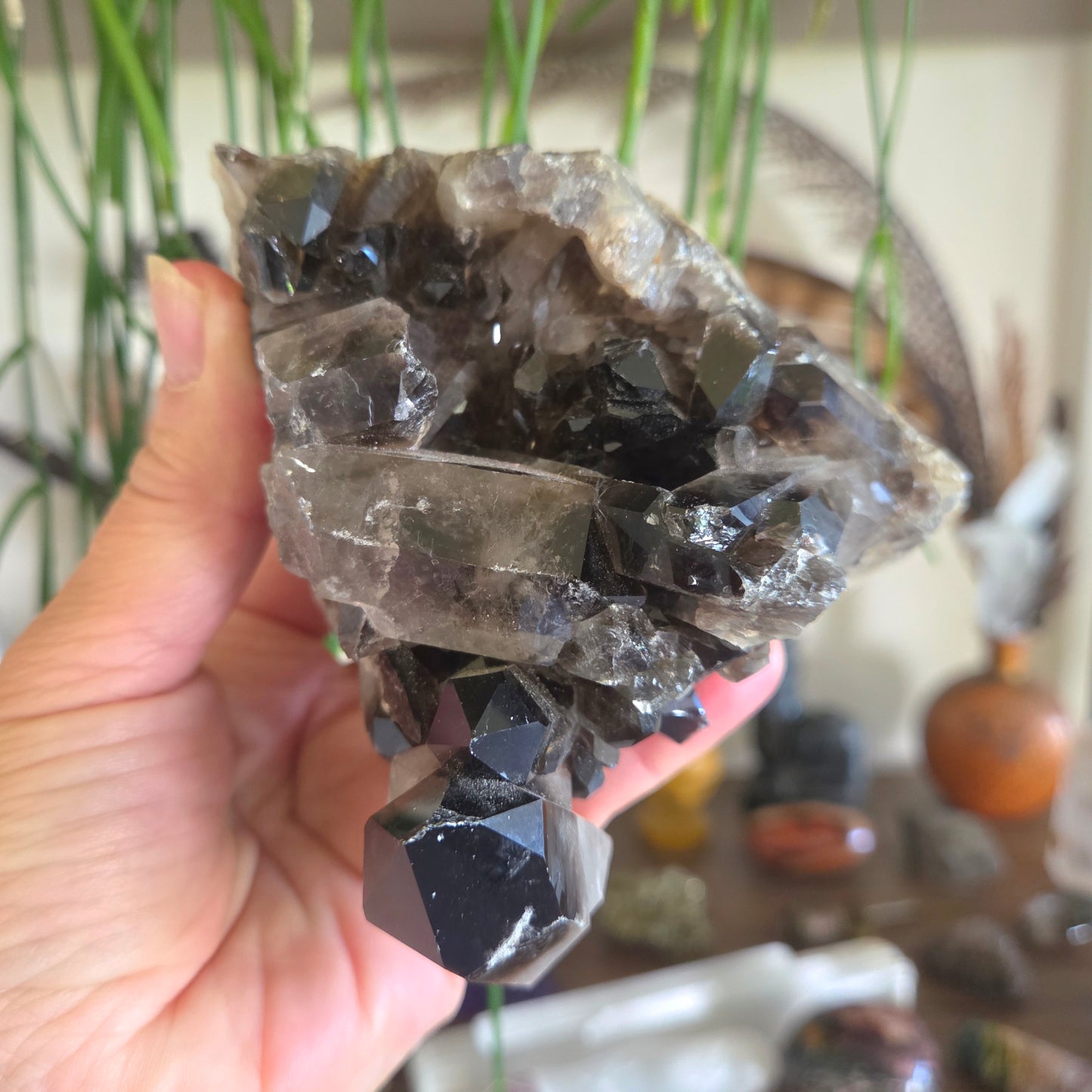 Hand holding a large crystal with a blurred indoor background
