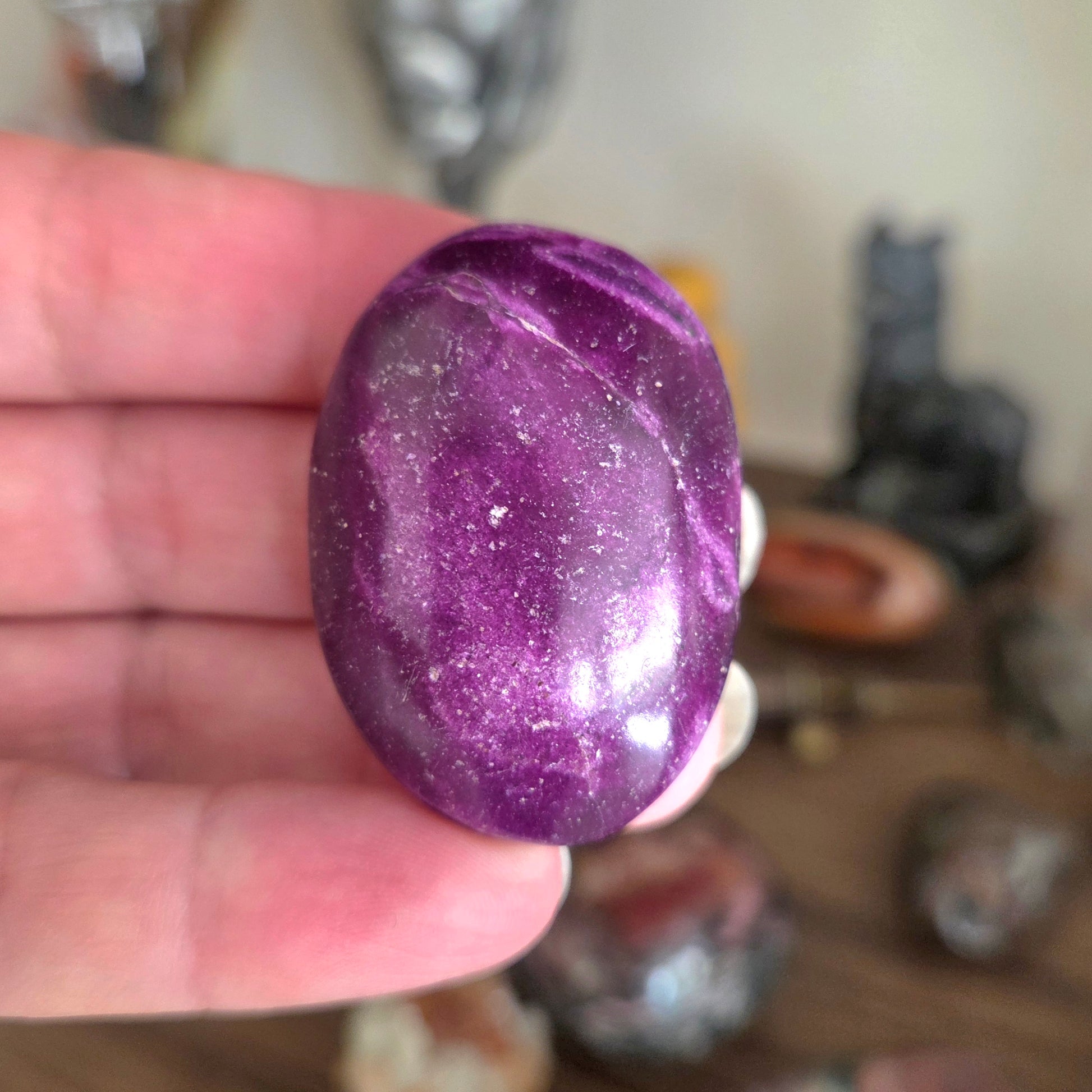 Purple stone held in a hand with a blurred background