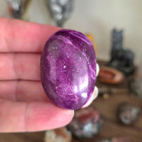 Purple stone held in a hand with a blurred background