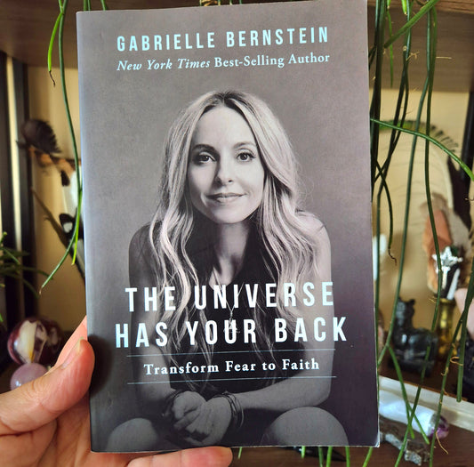 This image displays the cover of the book titled "The Universe Has Your Back" by Gabrielle Bernstein. The cover features a black and white photograph of Gabrielle Bernstein, a well-known author and speaker, with a gentle and welcoming expression.