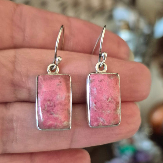 A pair of pink thulite earrings with metallic silver hooks.