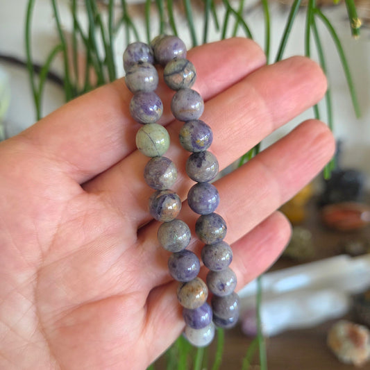 Hand holding a beaded bracelet with a natural stone pattern against a blurred background