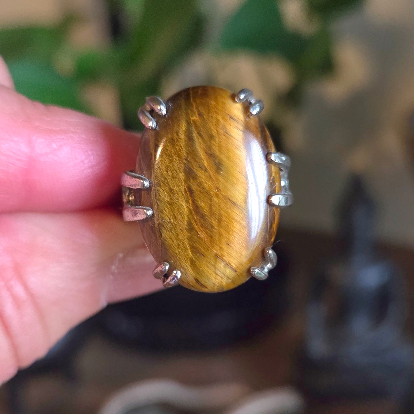 Ring with a large brown stone held by a hand against a blurred natural background