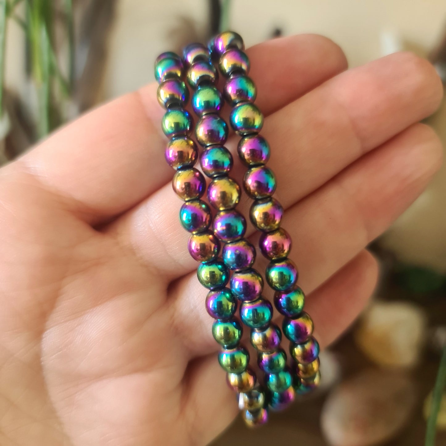 A multicolored beaded bracelet held in a person's hand, with a variety of colors including blue, green, and purple.
