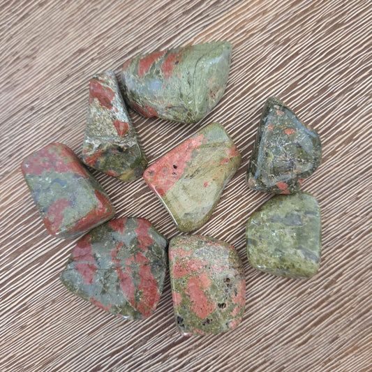Collection of green and red stones on a wooden surface
