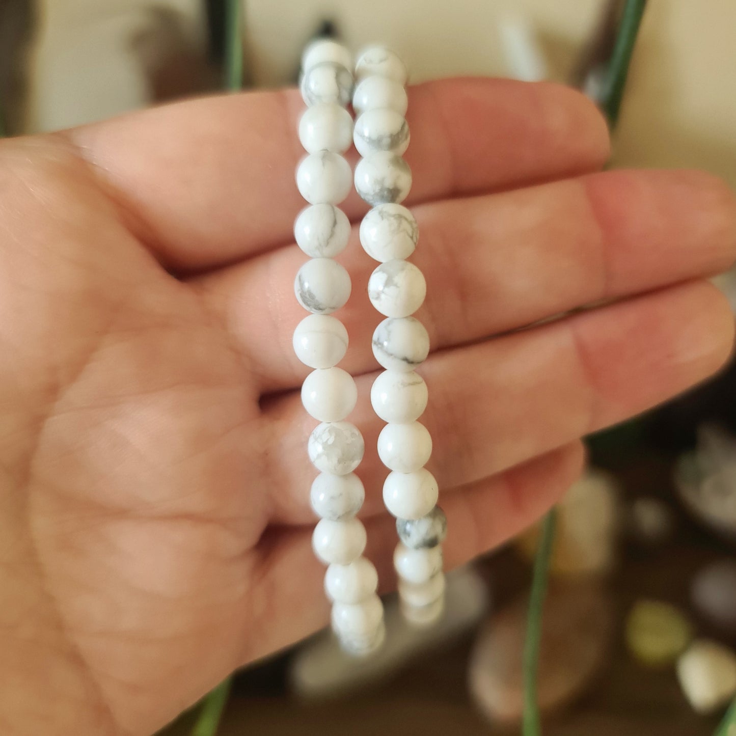 Two bracelets with white tumbled Howlite beads, one displayed in hand showing the size and design.