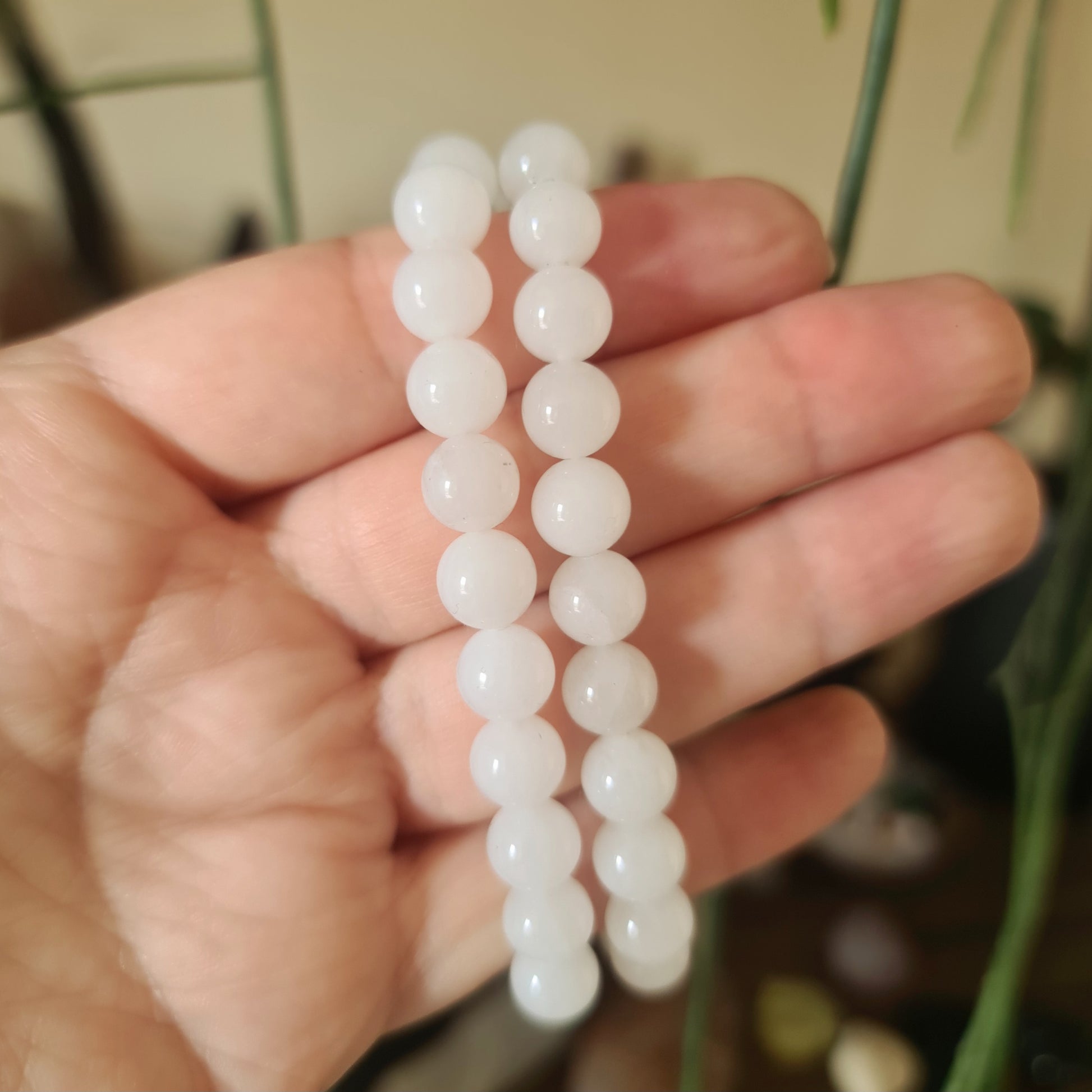 A person holding a white jade bracelet with a smooth, polished finish.