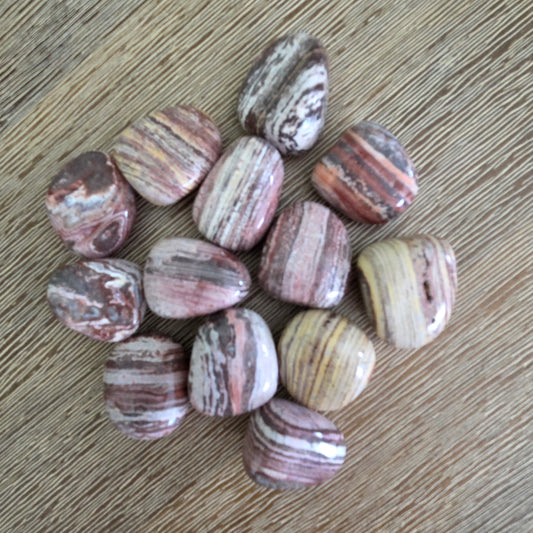 Polished stone beads with striped patterns on a wooden surface