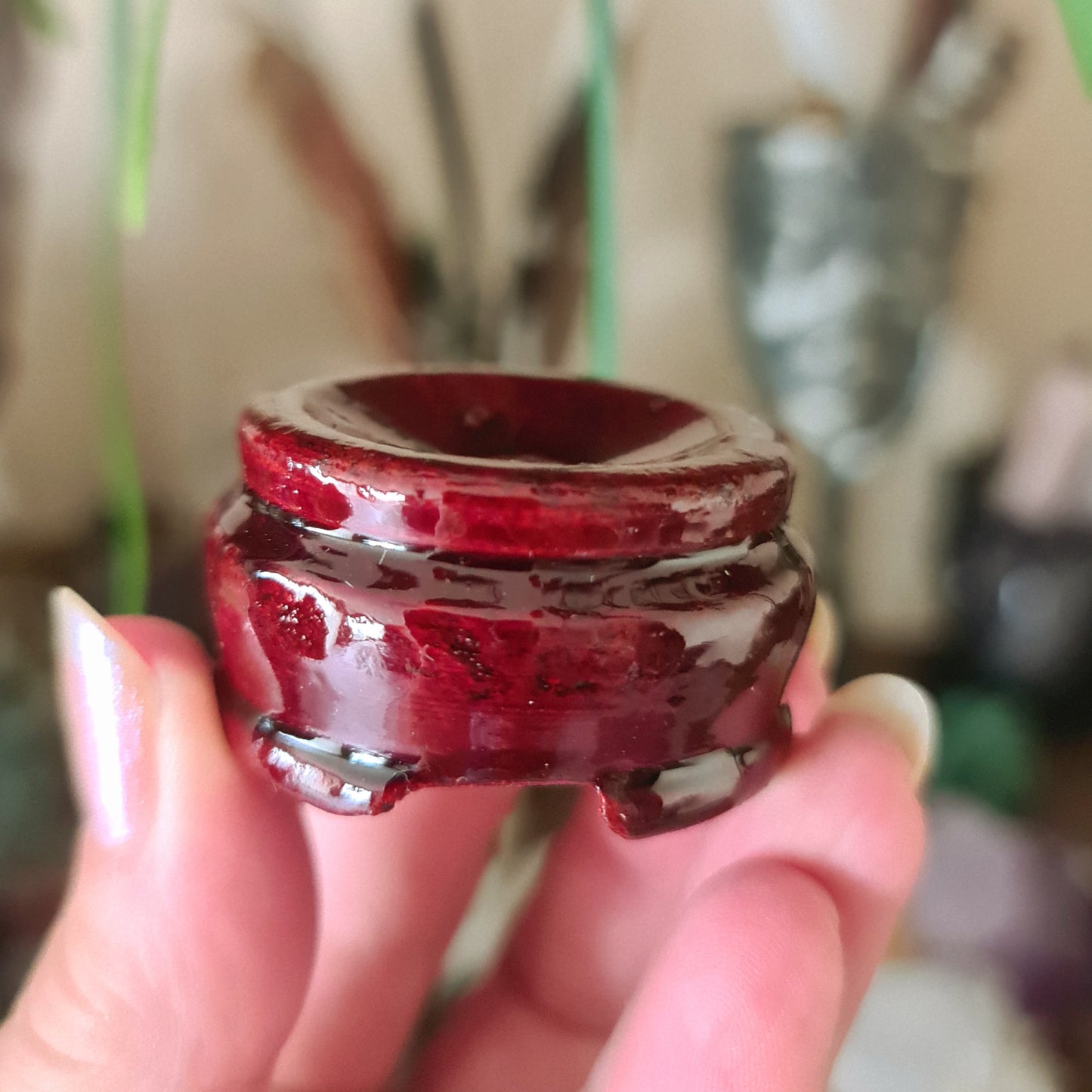 A person holding a medium-sized red wooden sphere, which is designed to stand as a display stand for medium to large spheres.