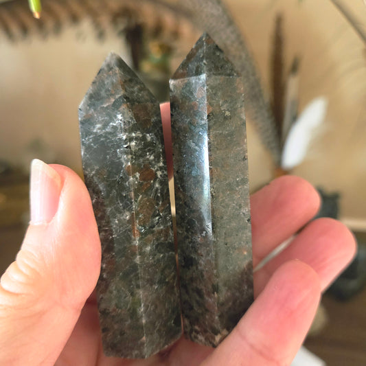 Two polished Yooperlite crystals held in a person's hand, showing a dark, smoky appearance.