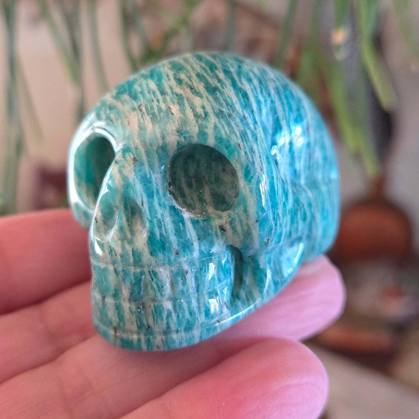 Blue marbled skull-shaped object held in a hand with a blurred background