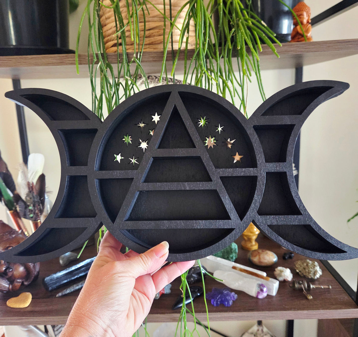 Black triangular symbol with moon phases held by a hand against a mystical background.