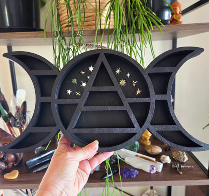 Black triangular symbol with moon phases held by a hand against a mystical background.