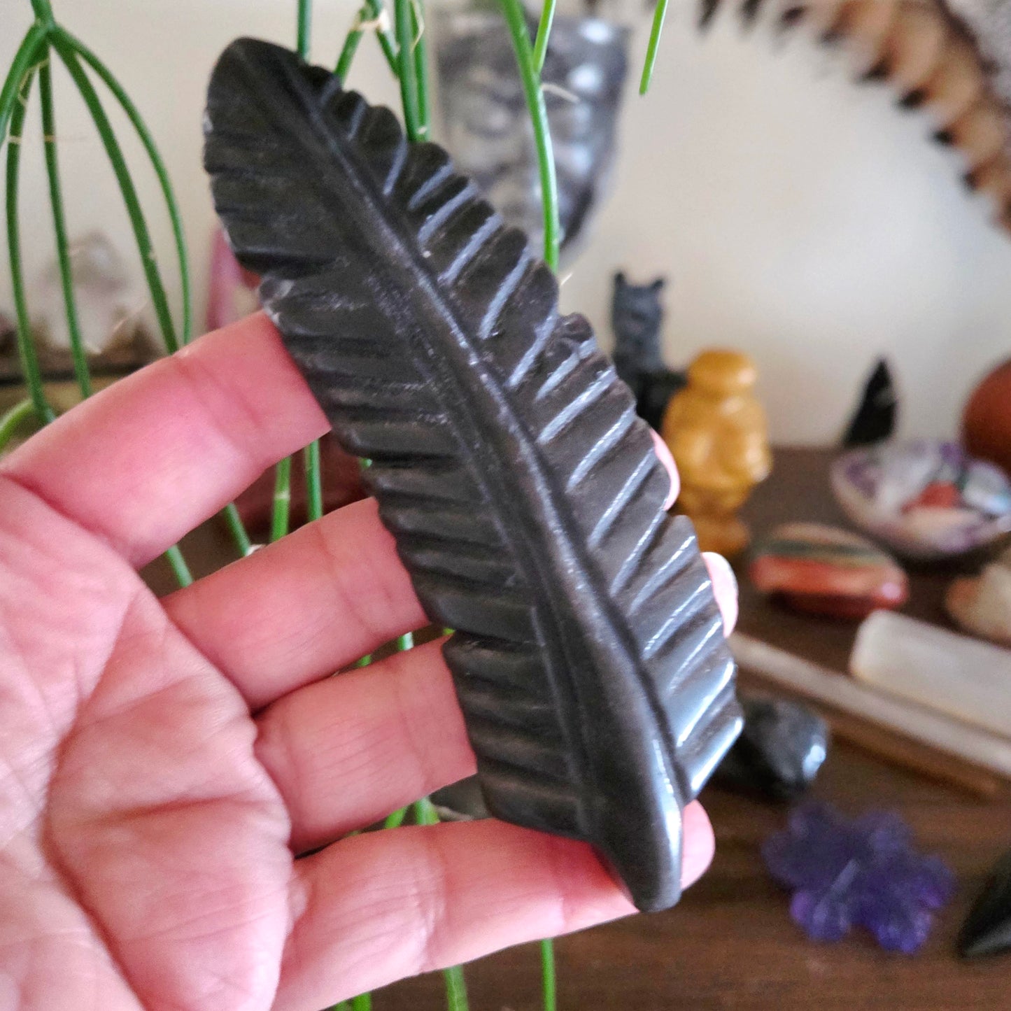 Hand holding a black leaf-shaped soap with a blurred background