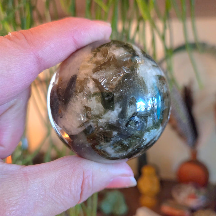 Hand holding a crystal ball with a blurred indoor background
