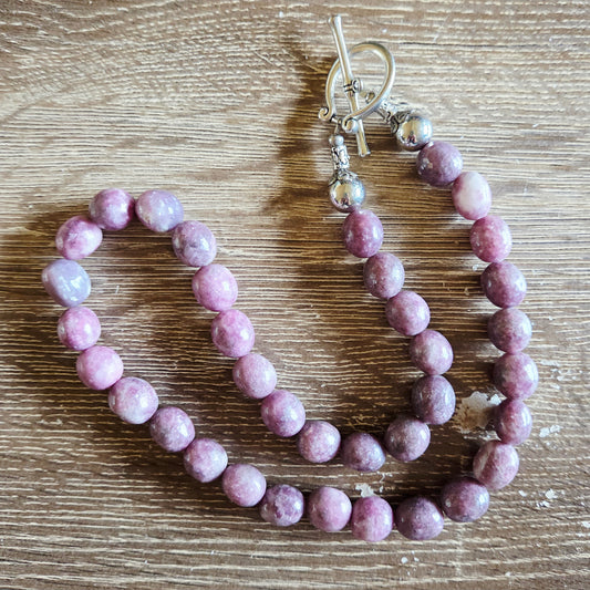 Purple beaded bracelet with silver clasp on a wooden surface