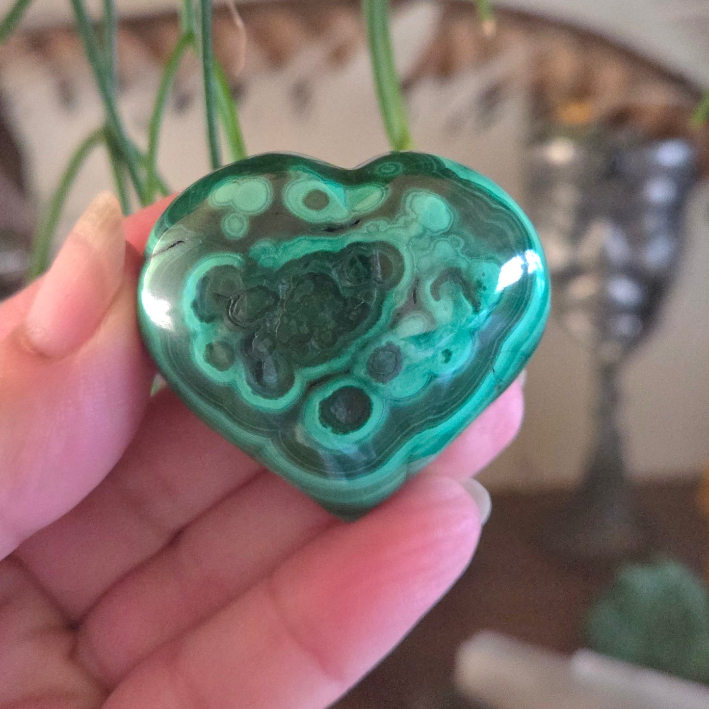 Heart-shaped green and black marbled stone held in a hand with a blurred background