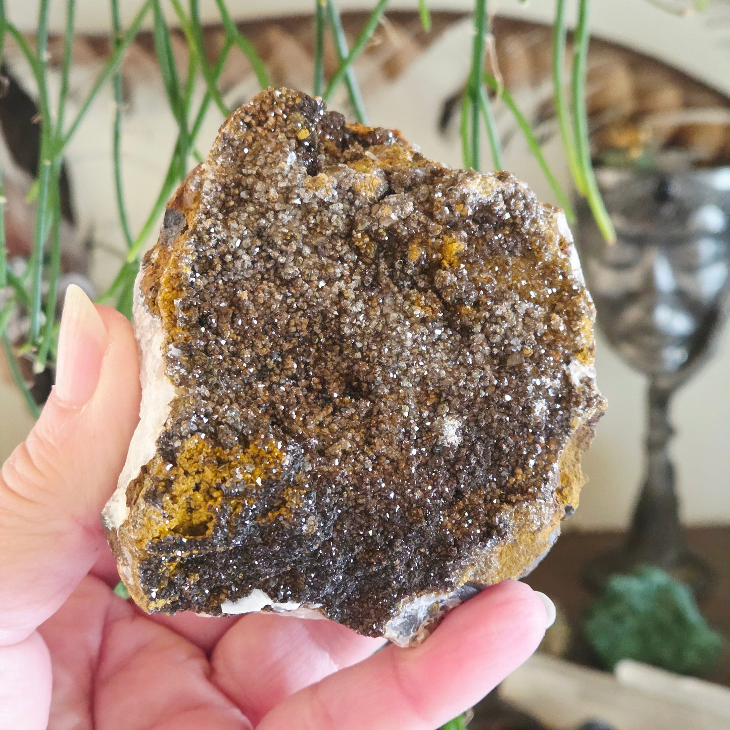 Hand holding a large mineral rock with a blurred indoor background