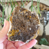Hand holding a large mineral rock with a blurred indoor background