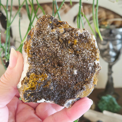 Hand holding a large mineral rock with a blurred indoor background
