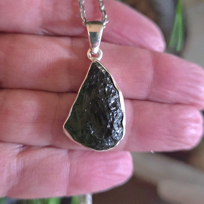 Pendant with a dark stone held in a hand
