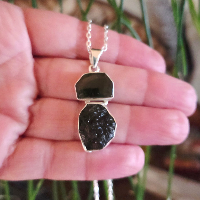 Necklace with a pendant held in a hand against a blurred natural background