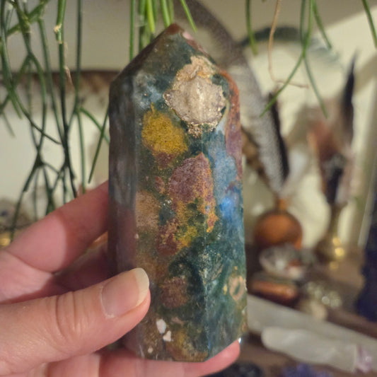 Hand holding a colorful crystal with a blurred background