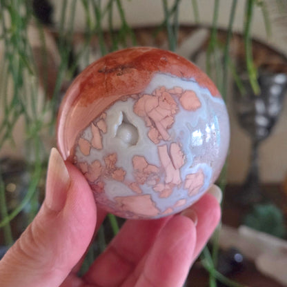 Person holding a decorative stone with a floral pattern against a blurred indoor background