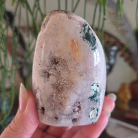 Hand holding a polished stone with natural patterns against a blurred indoor background
