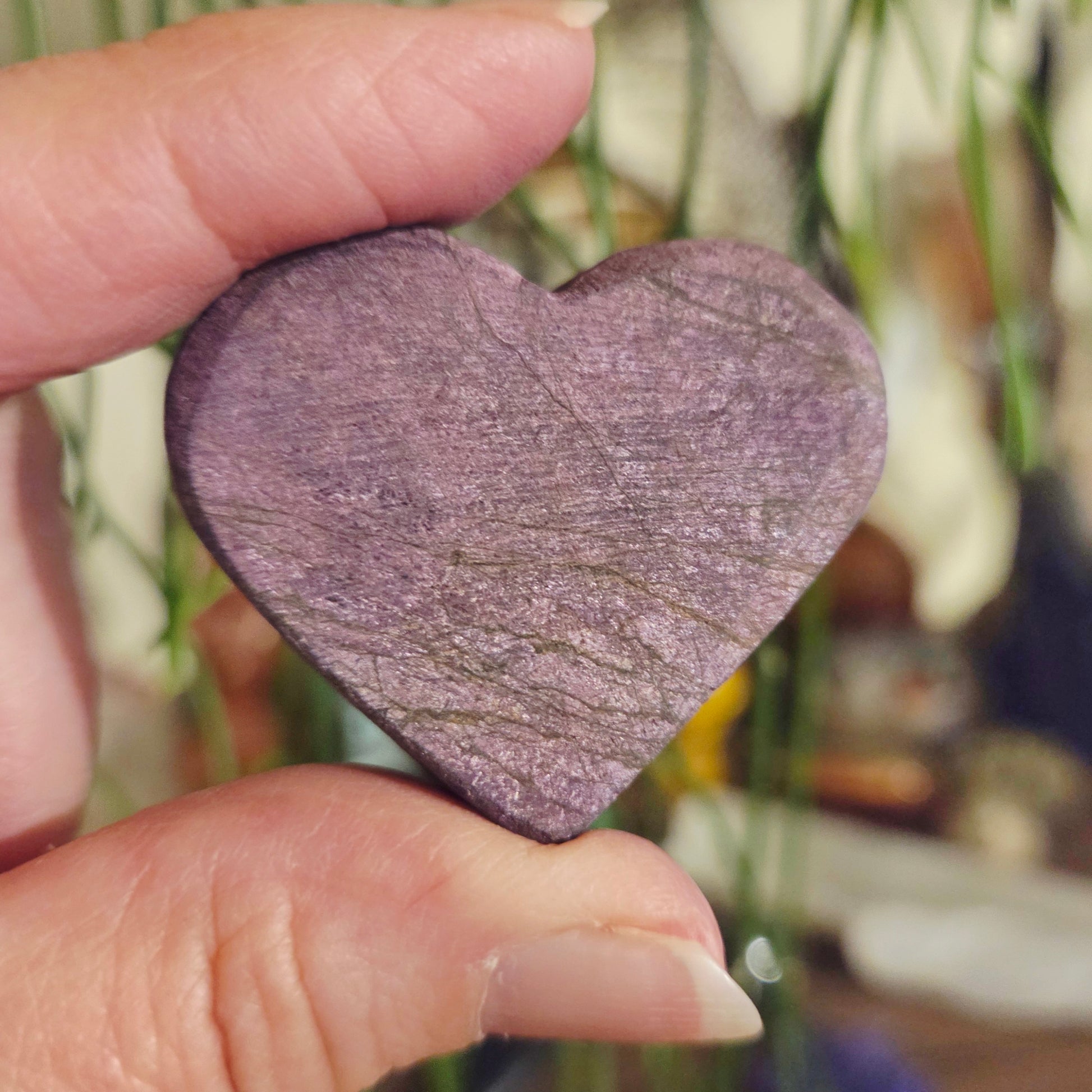 Heart-shaped stone held by a hand with a blurred background