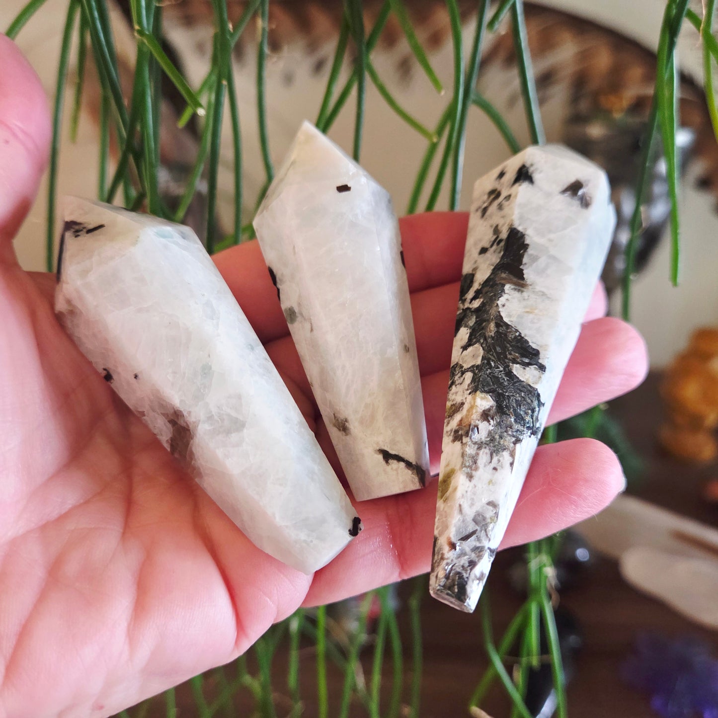 Three crystal-like objects held in a hand with a blurred natural background