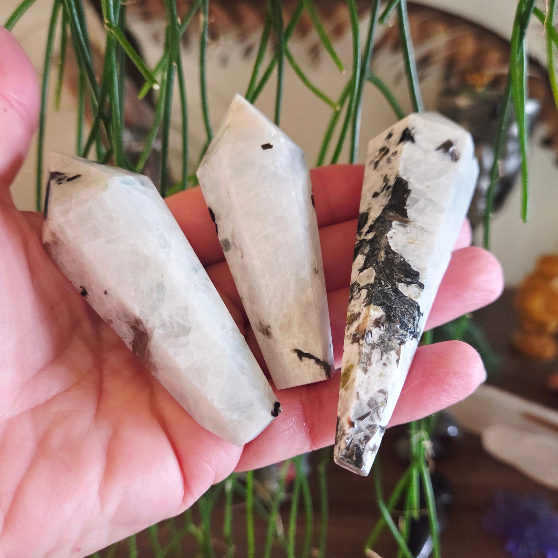 Three crystal-like objects held in a hand with a blurred natural background
