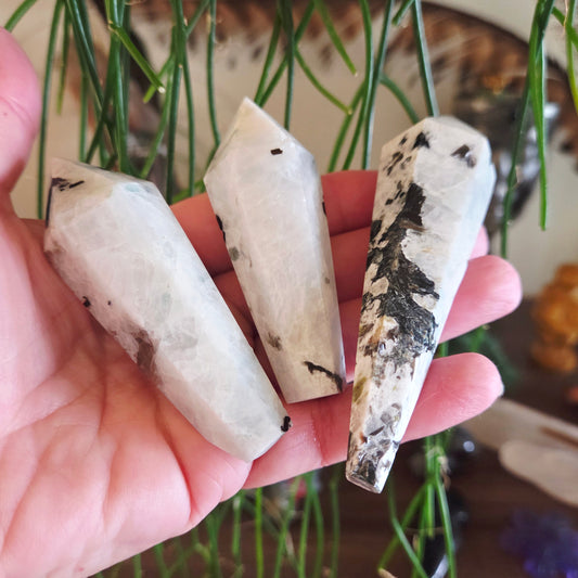 Three crystal-like objects held in a hand with a blurred natural background
