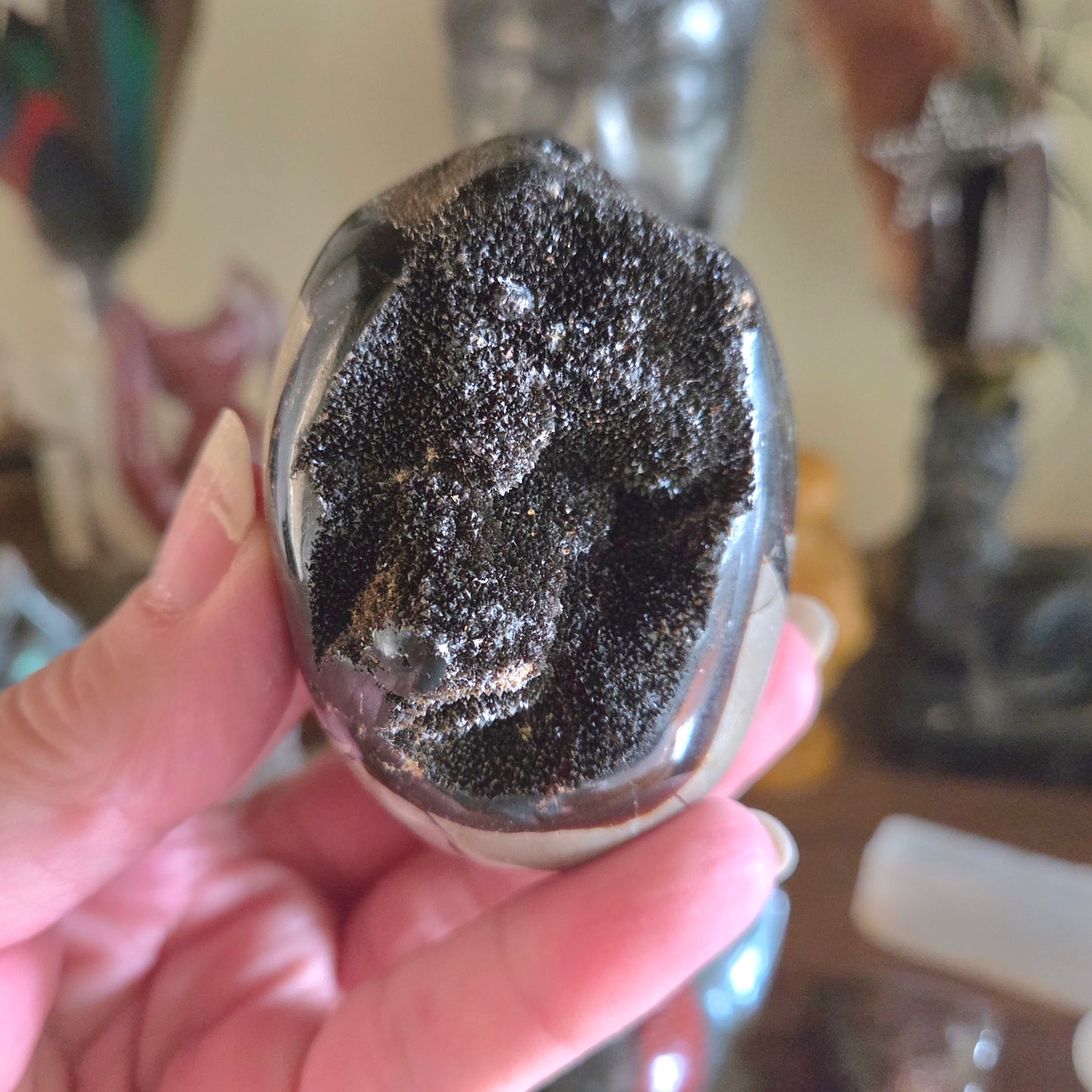 Hand holding a crystal with black and white patterns against a blurred background