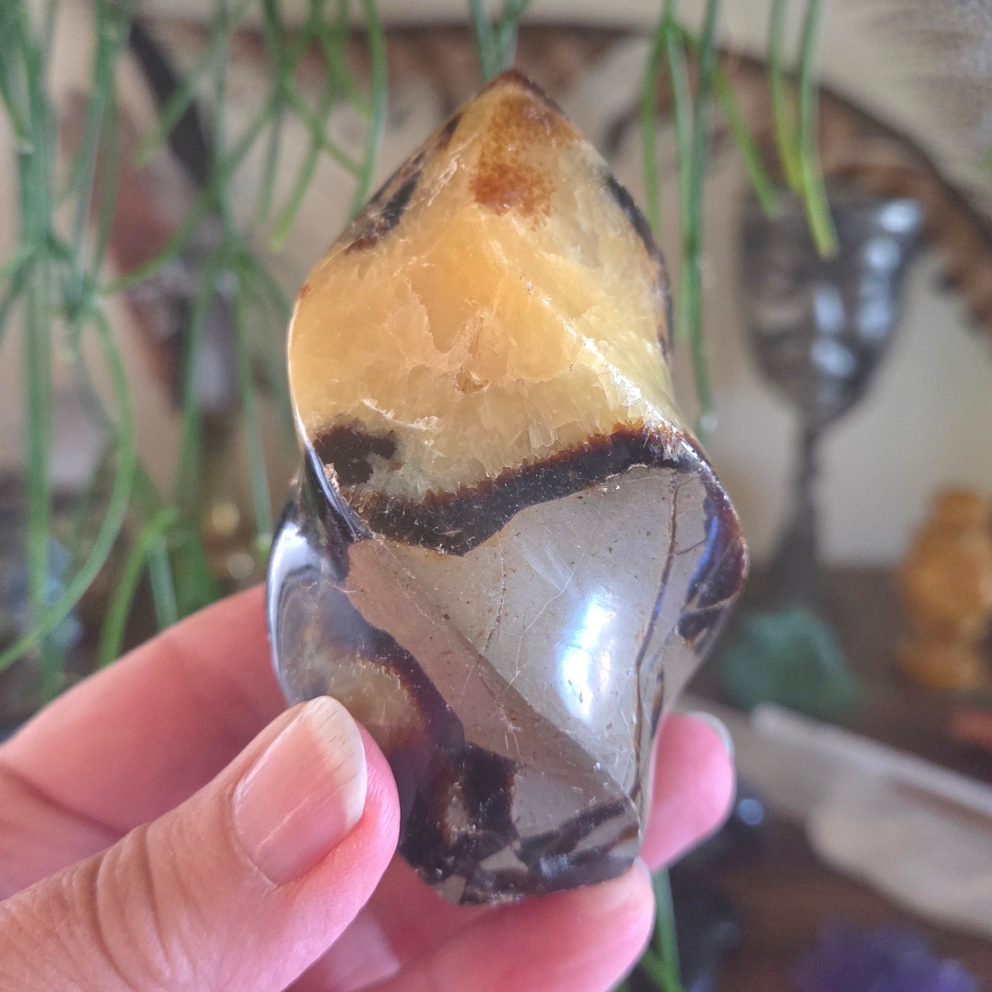 Hand holding a multicolored crystal with a blurred indoor background