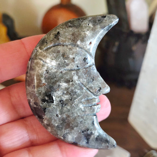 Hand holding a stone crescent moon-shaped object with carvings.