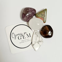 A collection of various crystal stones and decorative items on a white surface with a round label that reads 'Gemz on Gem'.